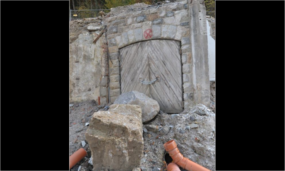 Der Eingang nach dem Abriss, durch einen Felsblock gegen unbefugten Zutritt gesichert. Eindringendes Grundwasser fließt durch ein Rohr ab